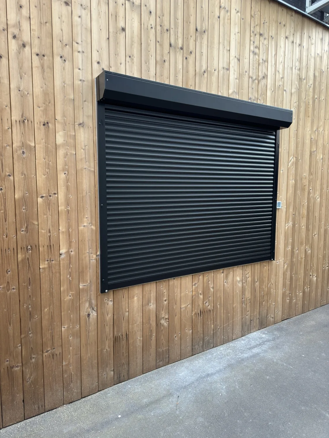 Zwart rolluik in houten gevel – realisatie Glas- & Schrijnwerken Tom Cools